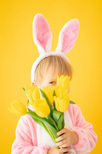 黄色背景下穿着复活节兔子的滑稽小孩