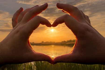 夕阳湖面心形的双手在夕阳的映衬下,在夏日的湖面或河面上,以多云的