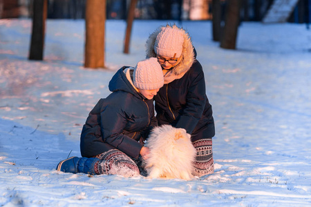 美丽的少女在冬天和斯皮茨狗玩得很开心