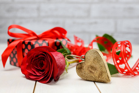 Valentines Day setting with red rose, wooden heart and  gift 