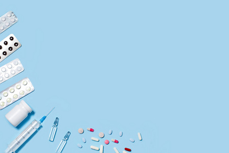 不同的药丸和胶囊,蓝色背景的注射器照片