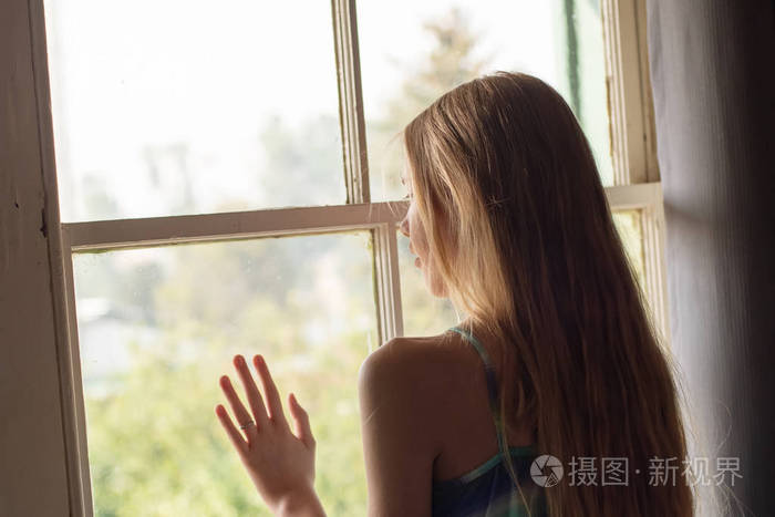 孤独的少女在房间里的窗户旁等着