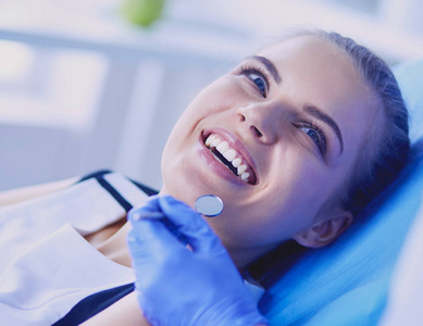年轻的女病人微笑着在牙医诊所检查牙齿。