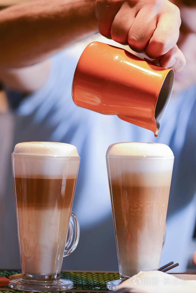 咖啡师在加牛奶的长咖啡上创作拿铁艺术咖啡杯中的拿铁艺术酒吧招待倒