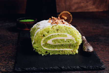 抹茶卷黑底黑盘子上的绿抹茶饼卷.选择性聚焦照片