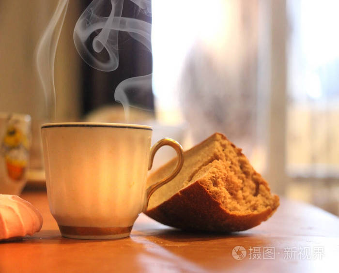 一杯咖啡和一片新鲜的面包放在木桌上