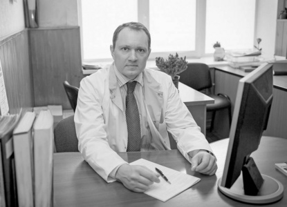 Doctor man sitting at the table at his workplace and smiling 