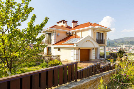 The facade of a beautiful white twostory cottage with a red roo