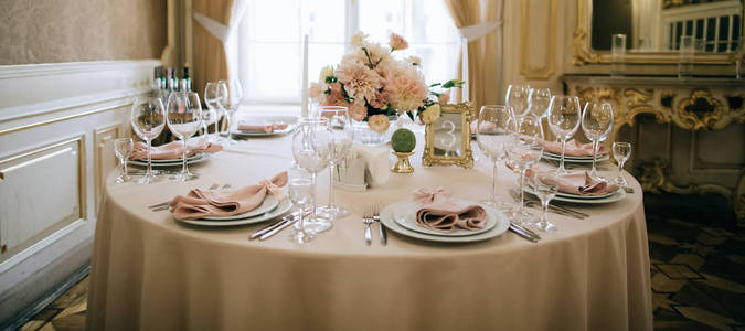 晚餐用圆桌餐具，餐具，玻璃杯，鲜花和蜡烛