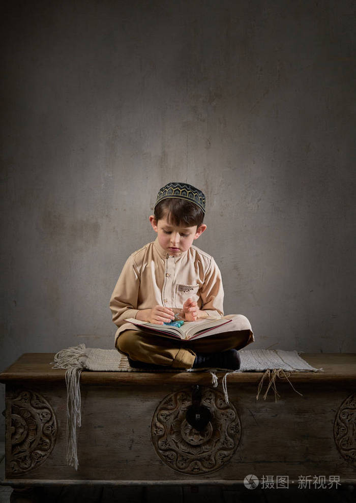 穿着阿拉伯衣服的穆斯林小男孩带着念珠读着古兰经祈祷真主斋月kareem