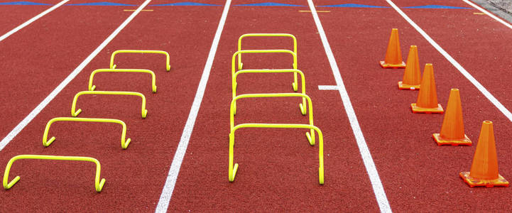 Mini hurdles and cones set up in lanes on a track for speed and 