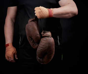 muscular athlete in a black uniform holds very old brown boxing 