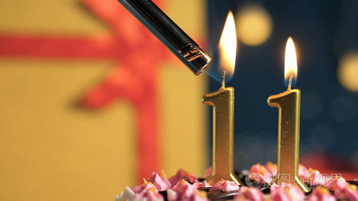 生日蛋糕编号11金色蜡烛点燃打火机背景礼物黄色盒子系上红丝带特写