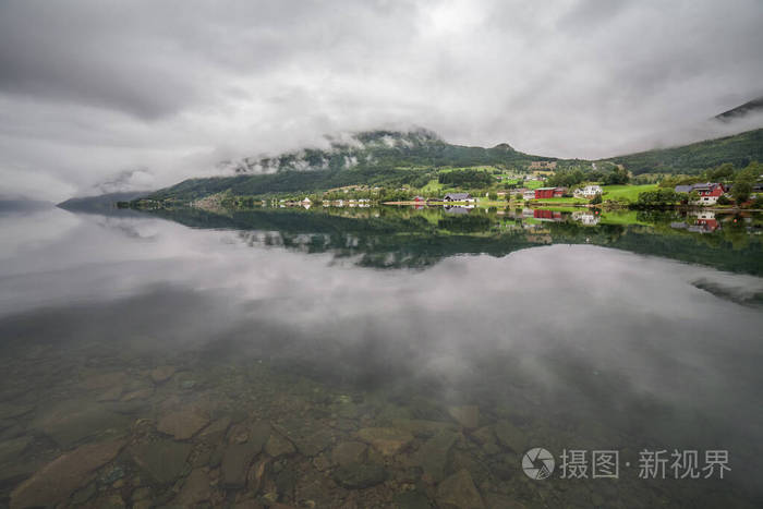 挪威的一个神秘的峡湾，山和雾悬挂在水面上，呈美丽的单色蓝色。