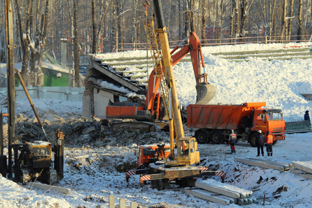 重卡汽车在俄罗斯,冬天,挖掘机在建筑工地把土装进卡车里,汽车起重机