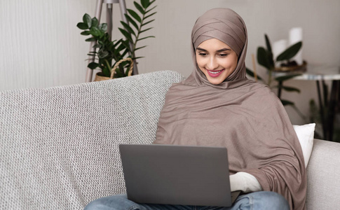 漂亮的阿拉伯女孩在家里用笔记本电脑上网聊天