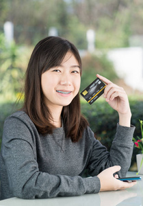 Young woman sitting showing credit card 