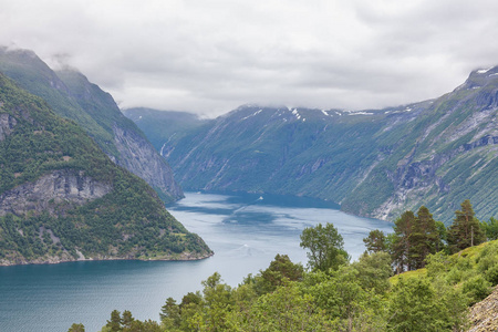 挪威的一个神秘的峡湾，山和雾悬挂在水面上，呈美丽的单色蓝色。