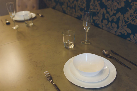 Empty plate and silverware set on wooden table.