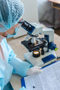 研究冠状病毒的女科学家。医生通过显微镜观察一种预防冠状病毒的疫苗。
