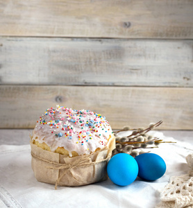 复活节蛋糕在一个浅色的背景上，在白色的餐巾上有蓝色的鸡蛋和美丽的柳枝。复制空间