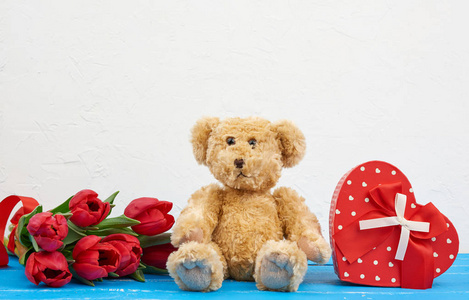 cute brown teddy bear sits on a blue wooden background, bouquet 