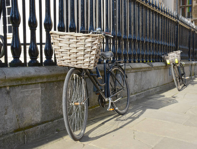 英国剑桥，学生骑着篮子靠着篱笆骑自行车