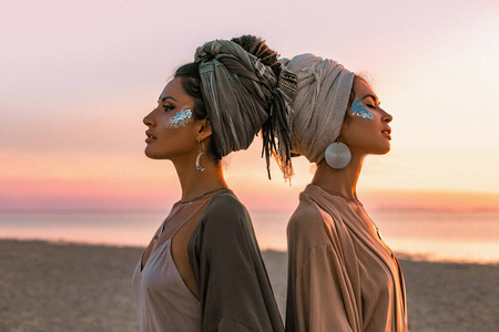 two young beautiful girls in turban on the beach at sunset 