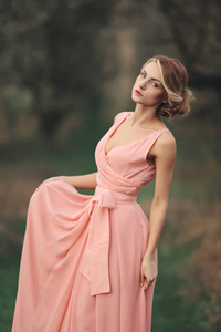 春天公园里的年轻时尚女人。金发女孩，发型穿着粉色连衣裙。选择性聚焦