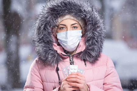 戴着医用防护面具,手里拿着白色,粉色,黄色的感冒药和流感药