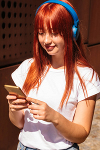 红发女人戴着耳机听无线音乐