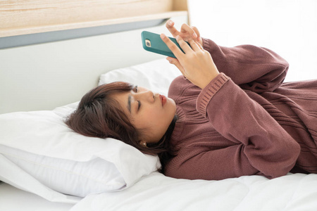Asian women playing smartphone on bed 