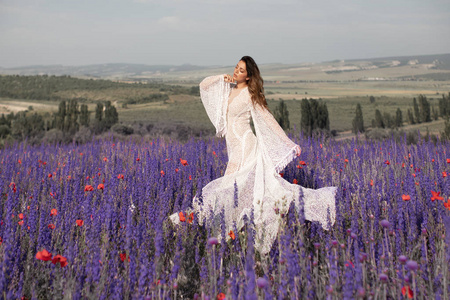 穿着白色礼服的新娘在淡紫色的田野里，带着薰衣草