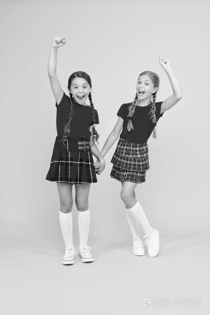 苏格兰风格小女孩穿格子连衣裙国庆节校服快乐的朋友女生们跳着黄色的
