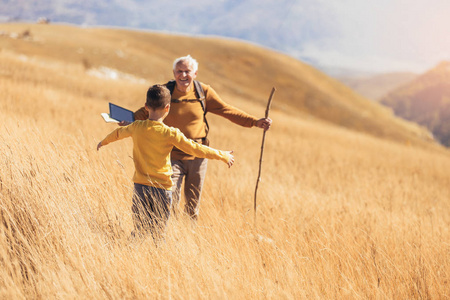 老人带着孙子在秋天的乡间散步。