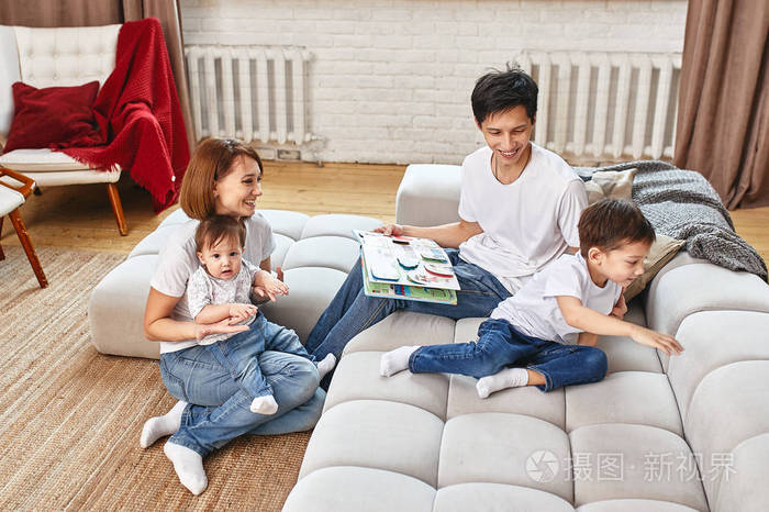 国际快乐家庭概念。爸爸妈妈儿子和小女儿在家里摆姿势照相，都在做家庭教育。家庭假期，父母，孩子和父母的概念。