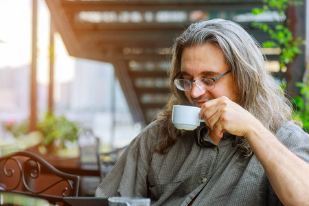 男人坐在那里喝咖啡，用笔记本电脑