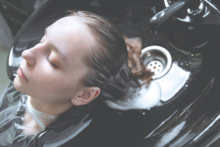 发型师在美发店为年轻金发女孩洗头照片