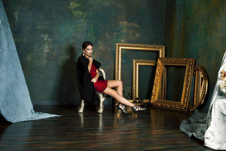 富丽堂皇的黑发女人在奢华的室内,空荡荡的金色镜框,是人们生活方式的