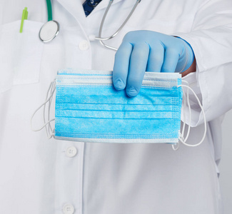 doctor in a white coat, blue latex sterile gloves holds textile 