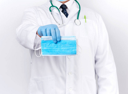 doctor in a white coat, blue latex sterile gloves holds textile 