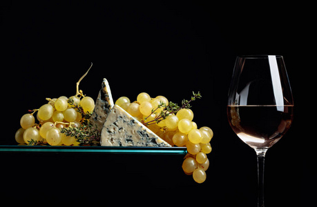 一杯白葡萄酒配零食。带蓝色奶酪的葡萄和你的