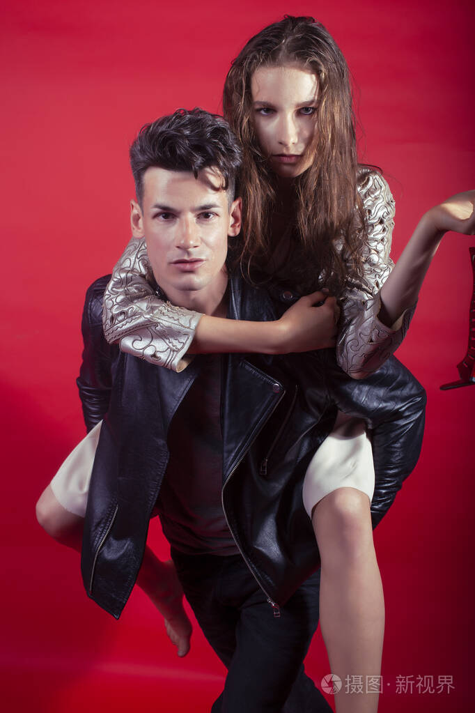 男女女在红色背景下手捧派对鞋摆造型,时尚风格让人眼前一亮照片-正版