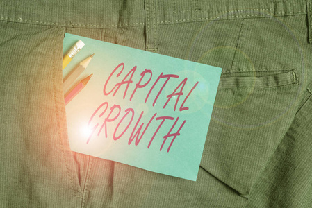 手写文字资本增长。概念意味着随着时间的推移，资产或投资的价值增加书写设备和蓝色便笺在工人工作裤口袋里。