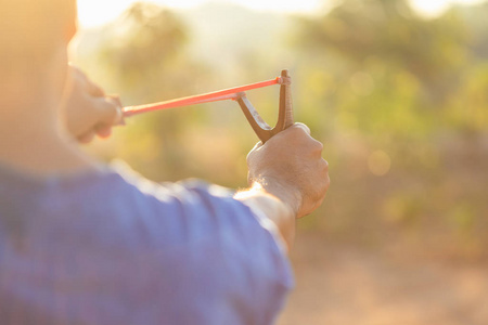 man playing slingshot or catapult in morning time with sunlight