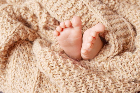 特写新生婴儿的脚在编织格子在一个有垂饰的ba