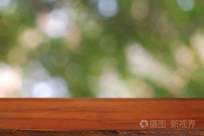 Empty wooden table in front of abstract blurred green bokeh ligh