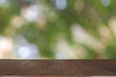 Empty wooden table in front of abstract blurred green bokeh ligh