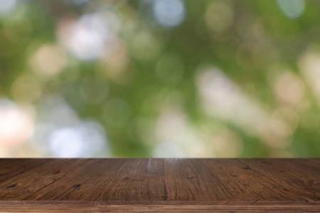 Empty wooden table in front of abstract blurred green bokeh ligh