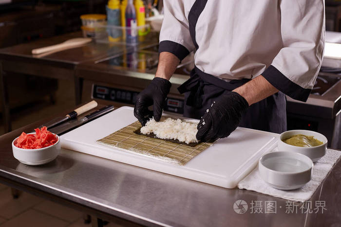 在餐厅厨房制作寿司和面包卷的过程。厨师手拿刀。